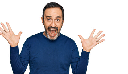 Middle age hispanic man wearing casual clothes celebrating crazy and amazed for success with arms raised and open eyes screaming excited. winner concept