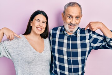 Hispanic father and daughter wearing casual clothes looking confident with smile on face, pointing oneself with fingers proud and happy.