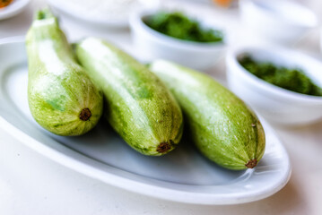 Baby zucchini on a white plate background. over white wooden table.  Organic food.