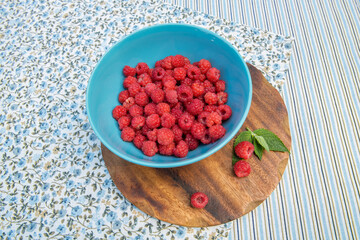 Bowl with fresh raspberries on the wooden board
