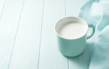 Blue mug of fresh milk on a wooden table. Fresh milk on a blue background