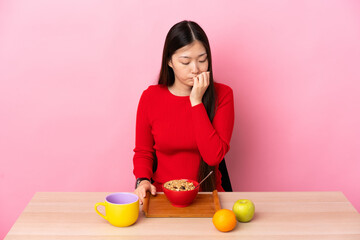 Young Chinese girl  having breakfast in a table having doubts