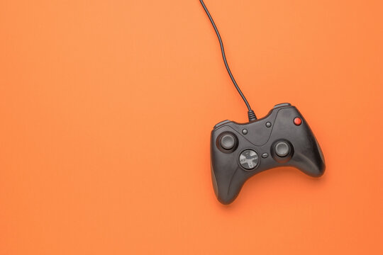 A gaming console on a bright orange background. Flat lay.