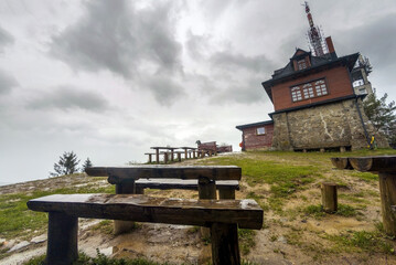 Wooden table and bench against viewpoint at a peak of Polish mountain called Lubon Wielki located in a region of Beskid Wyspowy famous for hike amongst tourists. A radio and tv broadcasting center - obrazy, fototapety, plakaty