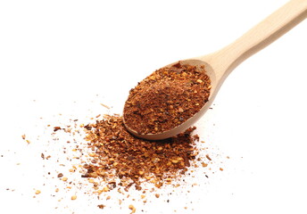 Crushed, ground red cayenne pepper, spicy chopped paprika in wooden spoon isolated on white background