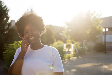 happy African American woman with a phone on the street in the summer