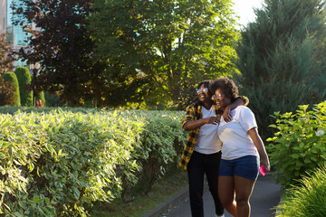 two happy African-American women are walking down the street in the summer