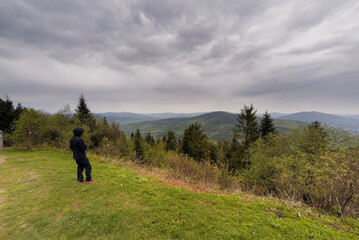 Wielki Lubon, Poland : An unidentified man in black clothes standing by the cliff admiring view of Lubon Wielki mountain located in Poland during overcast cloudy weather.