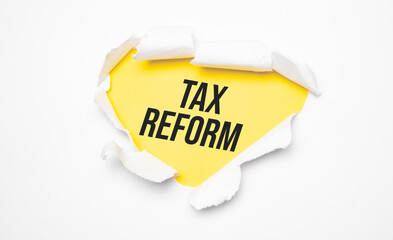 Top view of white torn paper and the text tax reform on a yellow background.