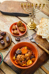 Jewish dish shut with meat on a wooden table near matzo and ingredients.