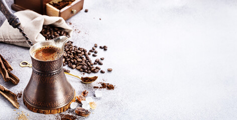 Turkish coffee brewing pot and beans on concrete background with copy space