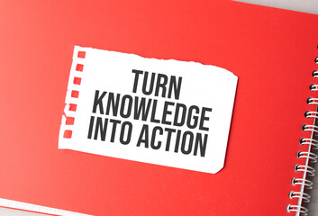 The word Turn Knowledge Into Action on torn paper on red notepad,.