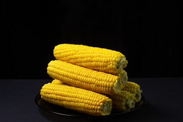 Boiled corn on a black background. Delicious sweet corn. Healthy food