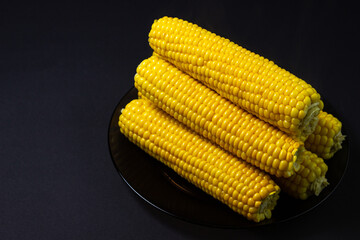 Boiled corn on a black background. Delicious sweet corn. Healthy food