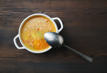 Bowl of soup and spoon on wooden background. Top view. Flat lay.