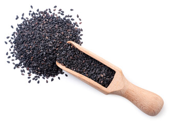 Black sesame seeds spilled out from a wooden scoop on a white background. Top view.