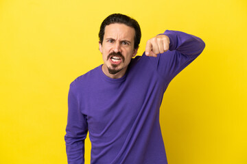 Young caucasian man isolated on yellow background frustrated and pointing to the front