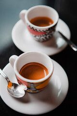 Traditional Italian coffee. Two small colorful espresso cups on a white saucer with a spoon on a...
