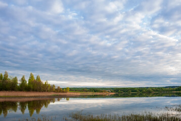 Autumn landscape with lake, trees with yellow leaves and sky with beautiful clouds.