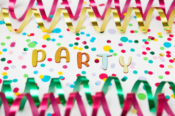 Colorful photo with letters of Party, paper streamers an confetti on white background.