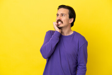 Young caucasian man isolated on yellow background is a little bit nervous