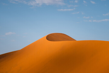 Fototapeta na wymiar Towering sand dunes in the Namib desert at sunrise near Sossusvlei, Namib-Naukluft National Park, Namibia, Africa.