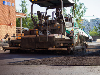 Fototapeta na wymiar Close-up back view of an road paver in the process of paving asphalt.