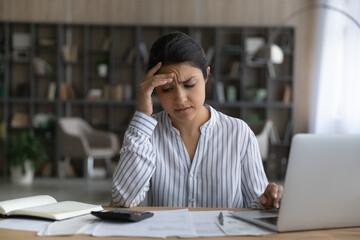 Unhappy young Indian woman distressed with debt or bankruptcy managing household finances or...
