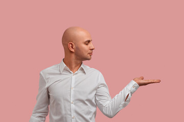 Blank for advertising. Satisfied bald man with bristle holds palm raised and keep copy space to...