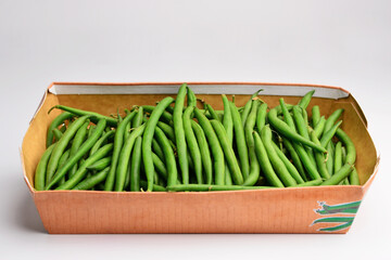 Bunch of green beans in a box on a white background. Green beans with case in market place. Fresh green beans on white background, top view. 
