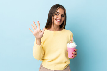 Young Uruguayan woman with strawberry milkshake isolated on blue background counting five with fingers