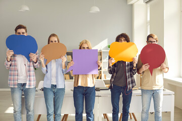 Group of college students holding multicolored empty cardboard and paper mockup speech bubbles covering their faces. Concept of young people expressing opinion and putting message across - obrazy, fototapety, plakaty