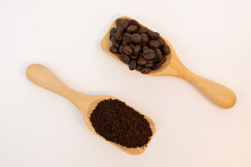 Coffee beans and ground coffee in wooden spoon isolated on white background.
