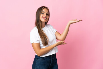 Young Uruguayan woman isolated on pink background extending hands to the side for inviting to come