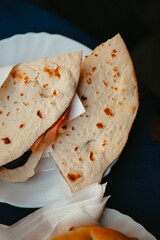 Traditional Italian food. Crispy panini and piadina sandwiches with prosciutto (speck), cheese, lettuce and vegetables with fresh drinks on a table with a blue tablecloth. Healthy European snack.