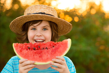Adorable baby girl in straw hat smile and eagerly eats juicy watermelon with summer sunshine on background