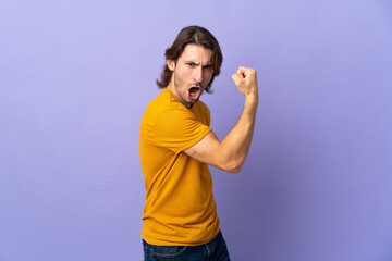 Young handsome man isolated on purple background doing strong gesture