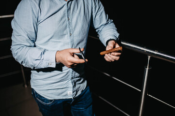 stylish man with a cigar on a dark background. Cigar clubs concept.