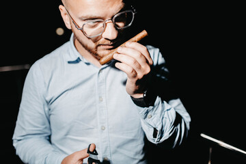 stylish man with a cigar on a dark background. Cigar clubs concept.