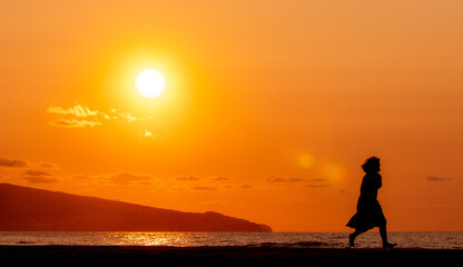 Woman at beach, during sunset, silhouette.