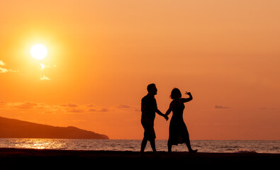 Harmony between couple at the beach, silhouette during sunset, lovers.