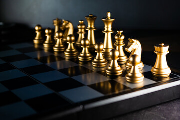 Horizontal shot of cool gold chess pieces in the starting position