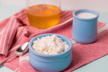 Cottage cheese in a blue bowl with sour cream and honey. Morning breakfast.