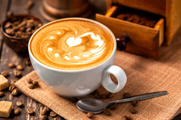 Hot coffee, decorated with milk latte heart shaped art, placed on a coffee bean sack, espresso