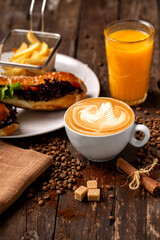 It is snack time, sandwich with latte coffee and orange juice in rustic style