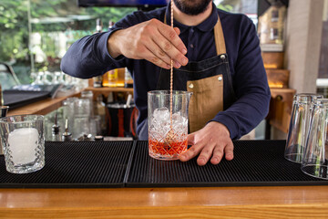 Bartender steering liquor and ice in a large cocktail glass