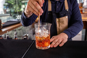 Bartender steering liquor and ice in a large cocktail glass