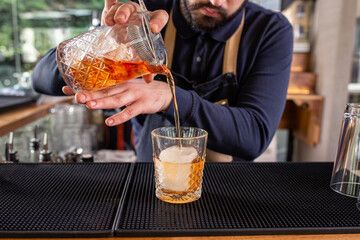 Male bartender pouring refreshing cocktail elixir into a glass cup