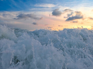 Naklejka premium Evening scenery on the beach, waves and water foam on the Pacific or carribean ocean coast bay with dramatic clouds on the sky, holidays in paradise. Sea and sunset or sunrise