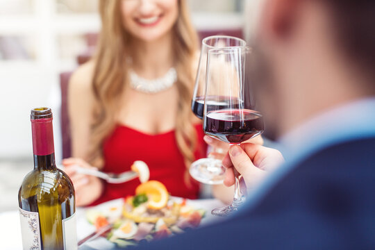 Couple toasting with red wine in romantic restaurant looking at each other
